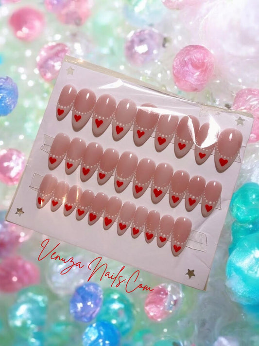 Faux ongles press-on rose nude à french blanche, nail art cœurs rouges et perles blanches, modèle romantique Venuza Nails.