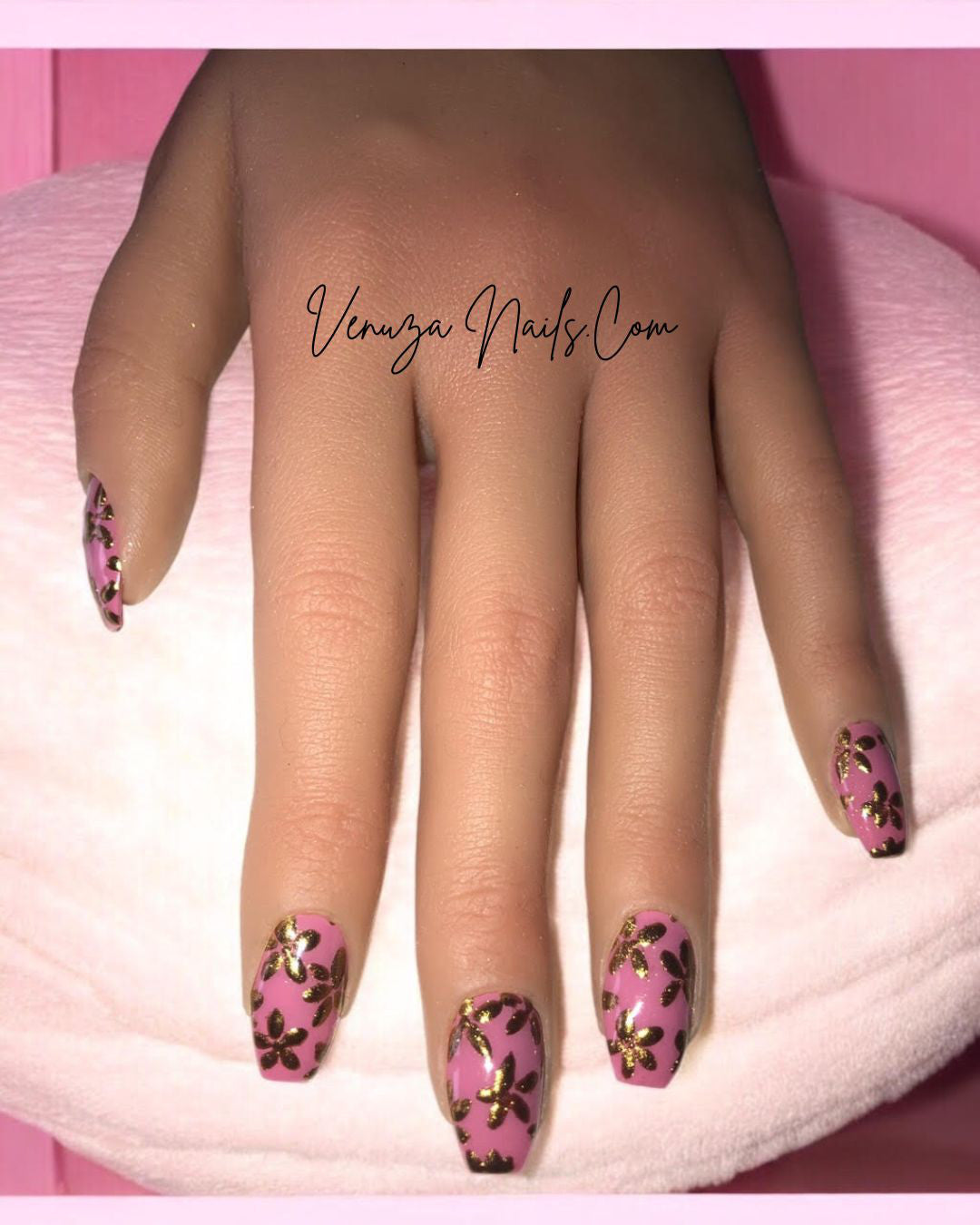 Main de femme présentant de beaux press on nails rose avec de fines fleurs dorées créations signées Venuza Nails