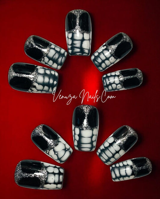 press-on nails longs, brillants, noirs avec reflets argentés et effet blooming blanc sur les extrémités, sur fond rouge