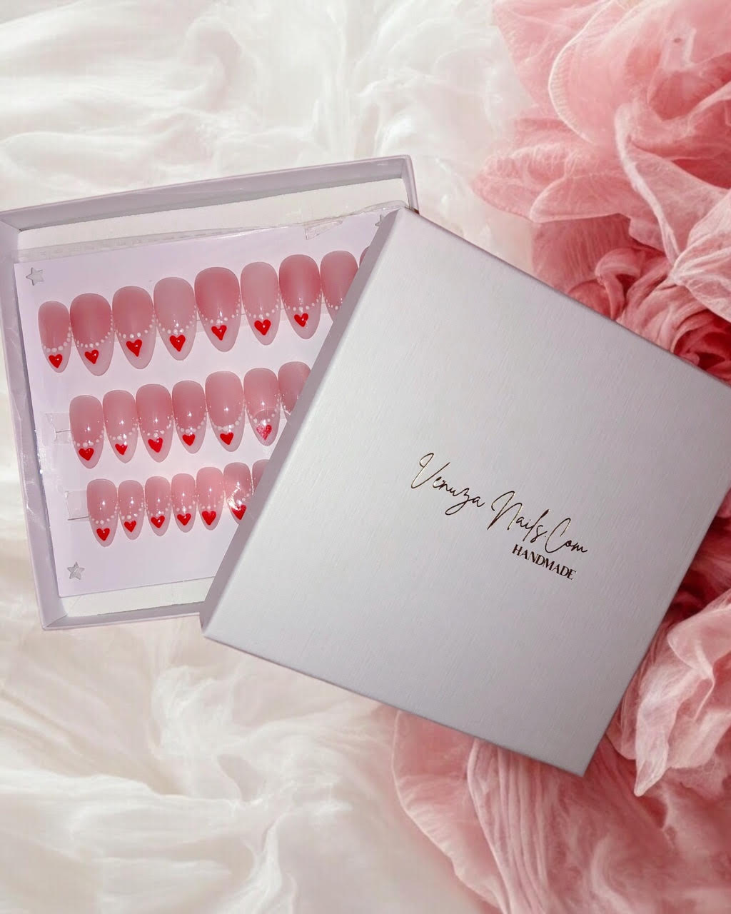 Faux ongles press-on rose nude à french blanche, nail art cœurs rouges et perles blanches, modèle romantique Venuza Nails.