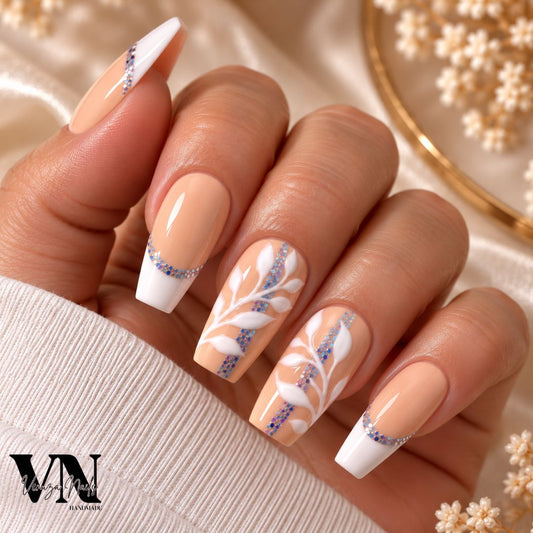 Faux ongles nude pêche avec French blanche, feuillage blanc en relief et paillettes holographiques argentées et multicolores, création artisanale Venuza Nails, forme coffin