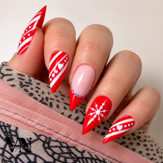 Faux ongles de Noël rouges effet bonbon avec lignes blanches, cœur et flocon de neige.