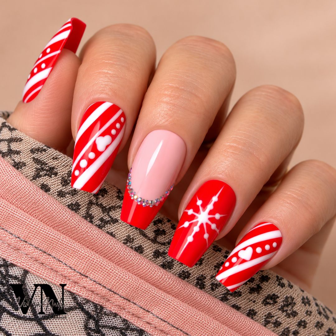 Manucure de Noël Santa en rouge et rose nude, décorée de rayures blanches, pois, cœurs et strass scintillants.