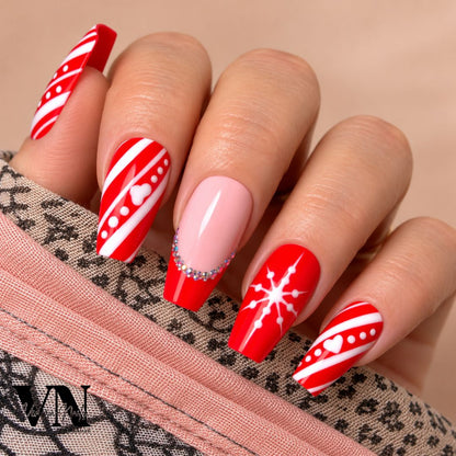 Manucure de Noël Santa en rouge et rose nude, décorée de rayures blanches, pois, cœurs et strass scintillants.