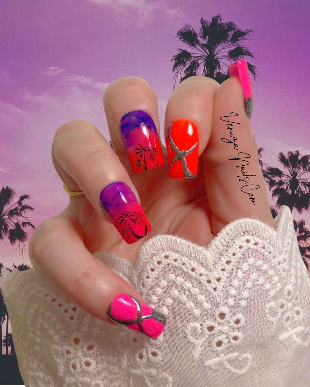 Press-on nails Caribbean Vibes aux dégradés tropicaux rose, violet et orange avec motifs palmiers noirs et détails métallisées argentées, fond coucher de soleil violet et palmiers.