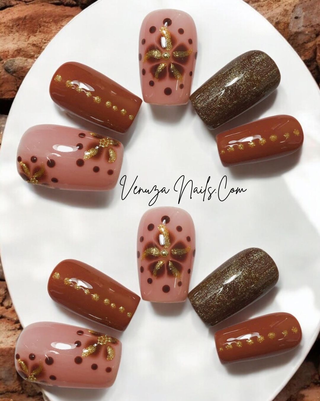 Ensemble de faux ongles press-on marron, rose poudré et doré avec motifs floraux scintillants, disposés sur un fond marroné et blanc.