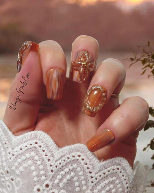 Manucure élégante avec les press-on nails “Amber Flora”, aux nuances boisées et fleurs dorées en 3D, mini perles dorées, parfaits pour l’automne.