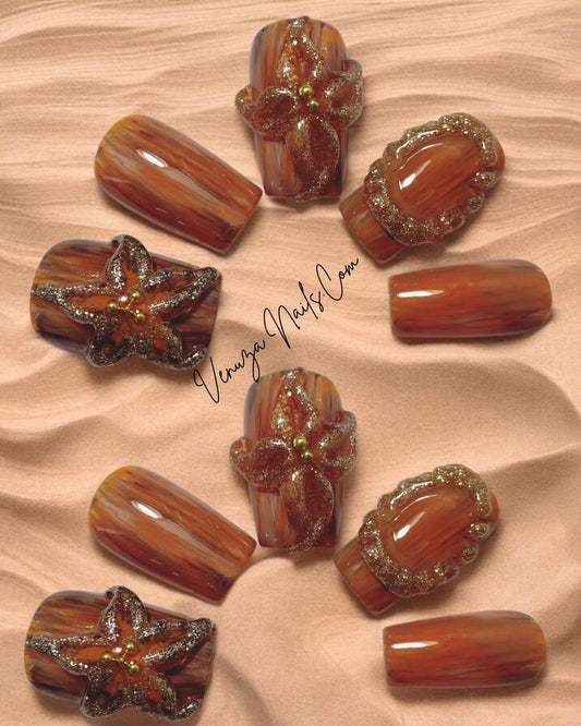 Press-on nails “Amber Flora” aux teintes boisées et motifs floraux dorés en 3D, inspirés de l’automne.
