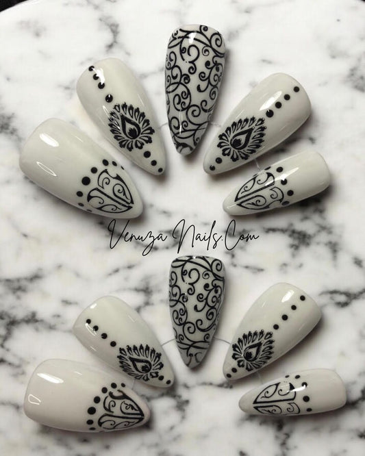  set de press on nails blancs aux motifs noirs de style baroque, avec arabesques , petits points délicats et volutes, peints à la main par Venuza Nails