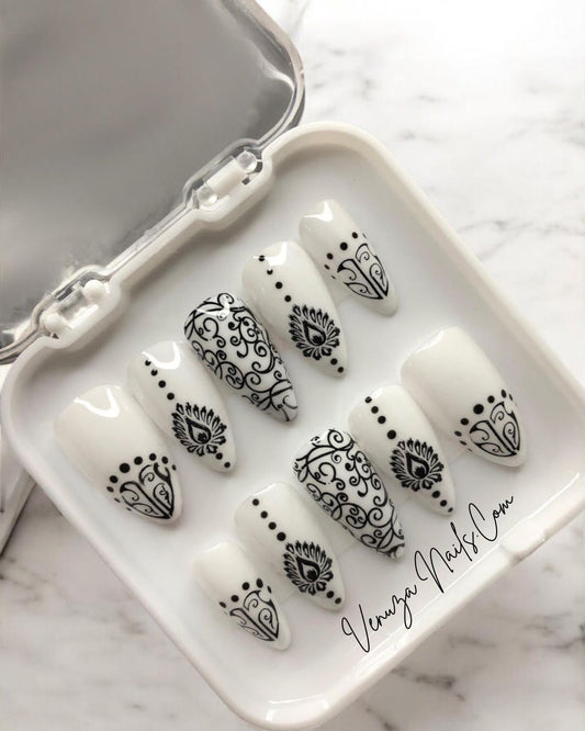  un set de press on nails présentés dans leur boite, ongles blancs aux motifs noirs de style baroque, avec arabesques , petits points délicats et volutes, peints à la main par Venuza Nails