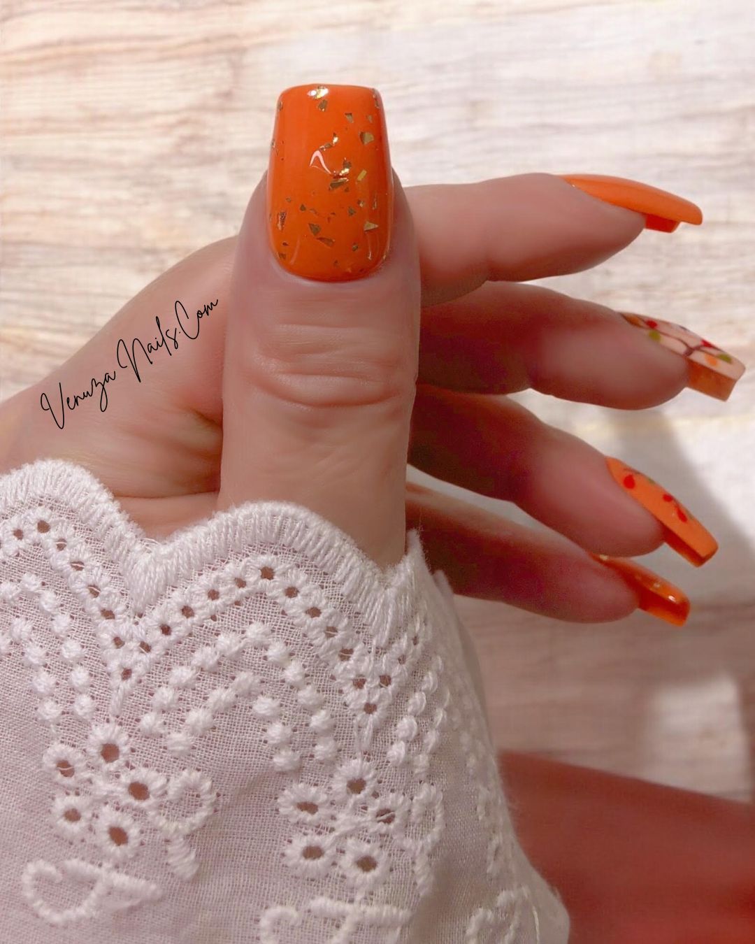 Modèle « Rêve d’Automne » de Venuza Nails porté sur une main féminine : press-on nails orange élégants ornés d’éclats de feuilles d’or, d’un motif de renarde endormie et de branches garnies de baies, pour une manucure automnale poétique et raffinée.