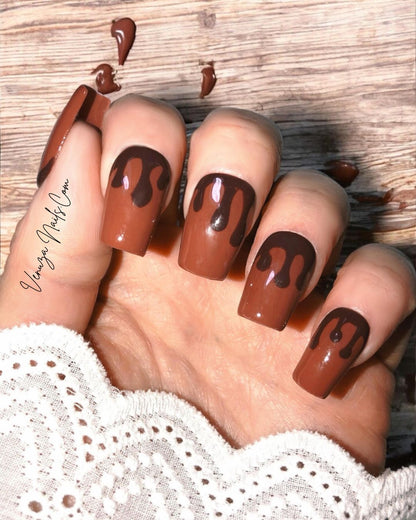 Press-on nails marron chocolat au design gouttes fondantes portés sur main de femme, pour un rendu élégant, sophistiqué et ultra gourmand, idéal pour la saison automnale.