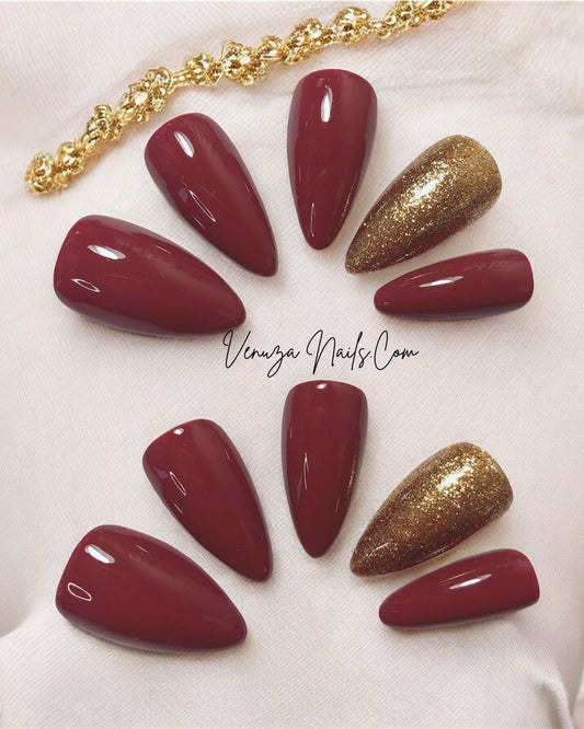posés a coté d'un bijoux en or, un kit de press on nails de couleur marron glacé, l'annulaire porte une teinte doré scintillante, signé Venuza Nails, tout est peint à la main .