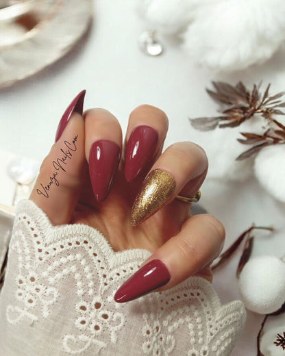main féminine portant un kit de press on nails de couleur marron glacé, l'annulaire porte une teinte doré scintillante, signé Venuza Nails, tout est peint à la main .
