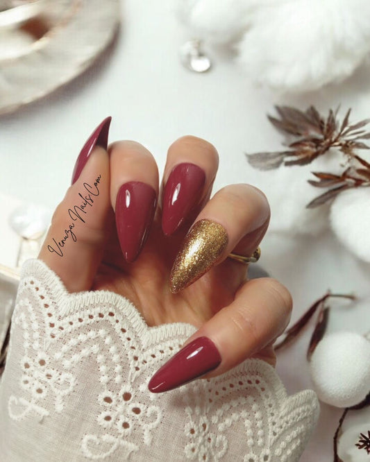 main féminine portant un kit de press on nails de couleur marron glacé, l'annulaire porte une teinte doré scintillante, signé Venuza Nails, tout est peint à la main .
