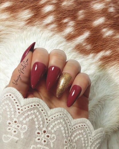 main féminine portant un kit de press on nails de couleur marron glacé, l'annulaire porte une teinte doré scintillante, signé Venuza Nails, tout est peint à la main .