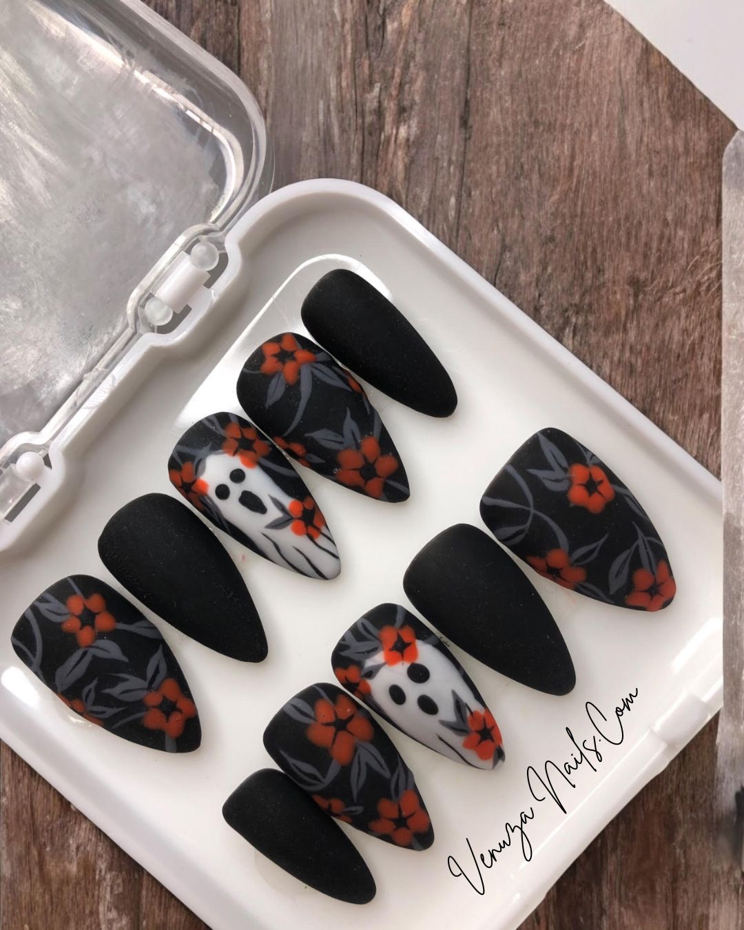 dans sa boite blanche, set  noir mat avec un feuillage gris orné de fleurs oranges avec sur le majeur un fantôme hurlant.