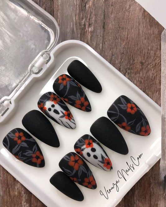 dans sa boite blanche, set  noir mat avec un feuillage gris orné de fleurs oranges avec sur le majeur un fantôme hurlant.