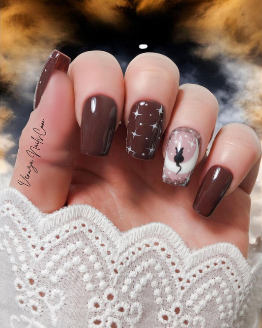 Press-on nails marron étoilés, avec motif de chat noir et lune sur fond rose clair – modèle Witchy Cat pour Halloween. signé Venuza Nails