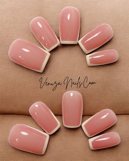 main de femme portant un set de dix ongles sur fond de cuir marron, french contour en carré medium, french manucure moderne et tres chic
