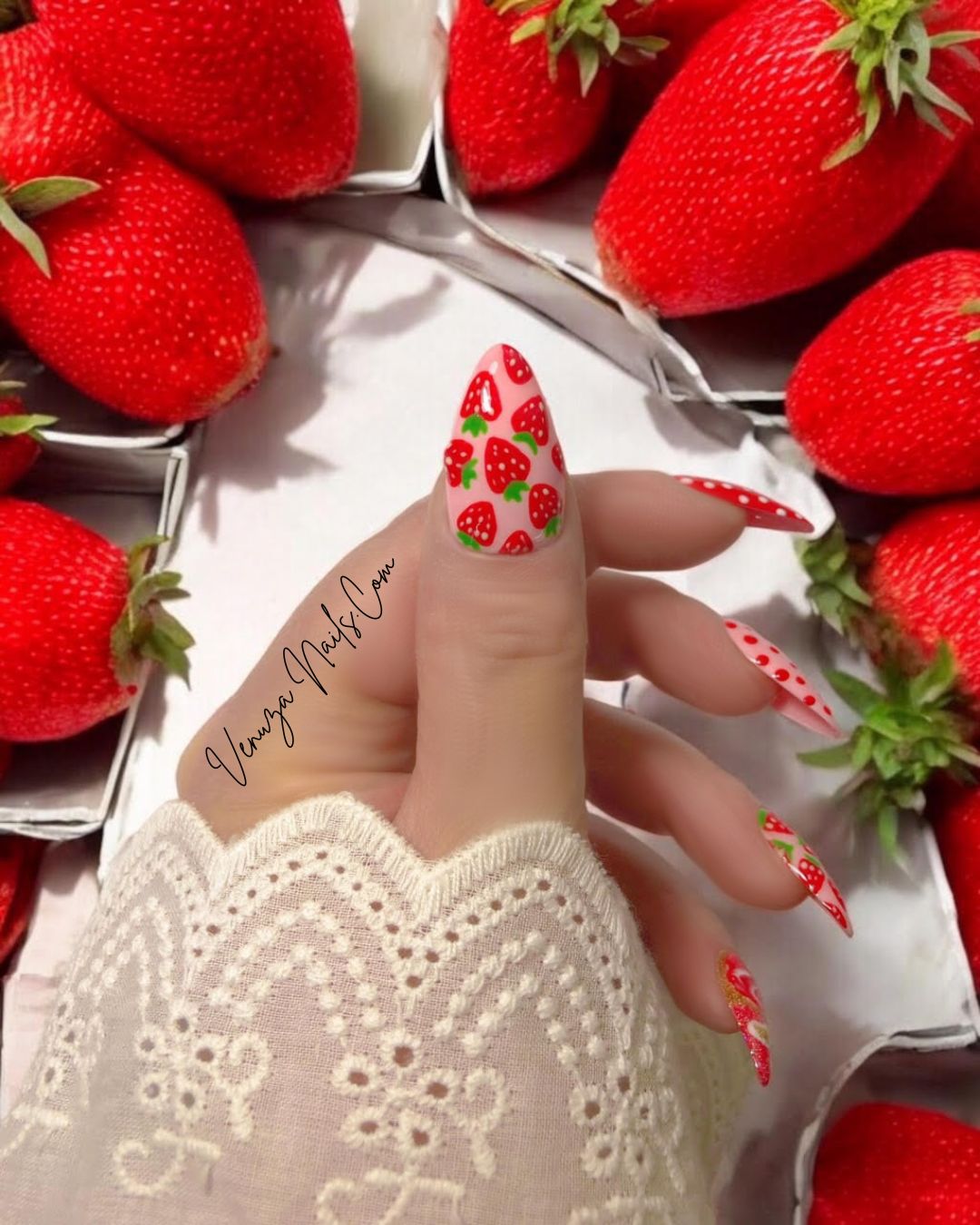 Press-on nails Venuza Nails modèle Fraizia, manucure rose et rouge décorée de fraises, pois et effet marbré, posés sur les mains pour un rendu élégant et fruité.