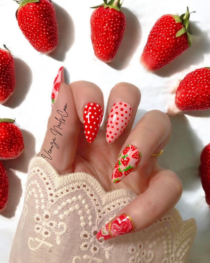 Press-on nails Venuza Nails modèle Fraizia, manucure rose et rouge décorée de fraises, pois et effet marbré, posés sur les mains pour un rendu élégant et fruité.