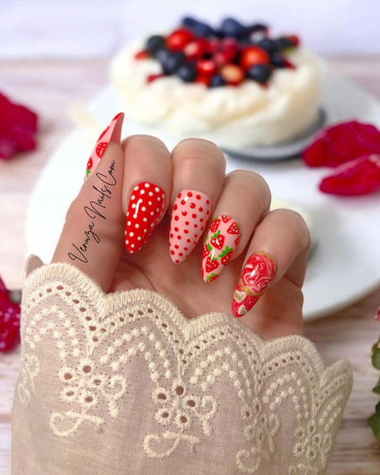 Press-on nails Venuza Nails modèle Fraizia, manucure rose et rouge décorée de fraises, pois et effet marbré, posés sur les mains pour un rendu élégant et fruité.