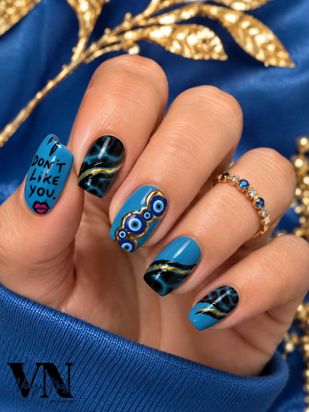 Press-On Nails Nazar Noir portés sur ongles carrés courts, nail art bleu, noir et or avec motifs œil turc et inscription « I DON'T LIKE YOU »