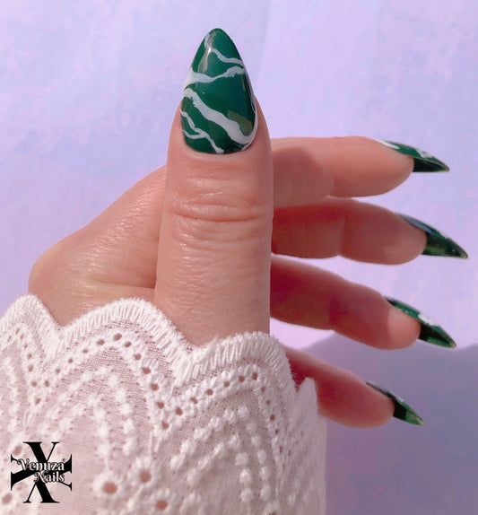 main dont pouce montrant les ongles marbrés vert et blancs