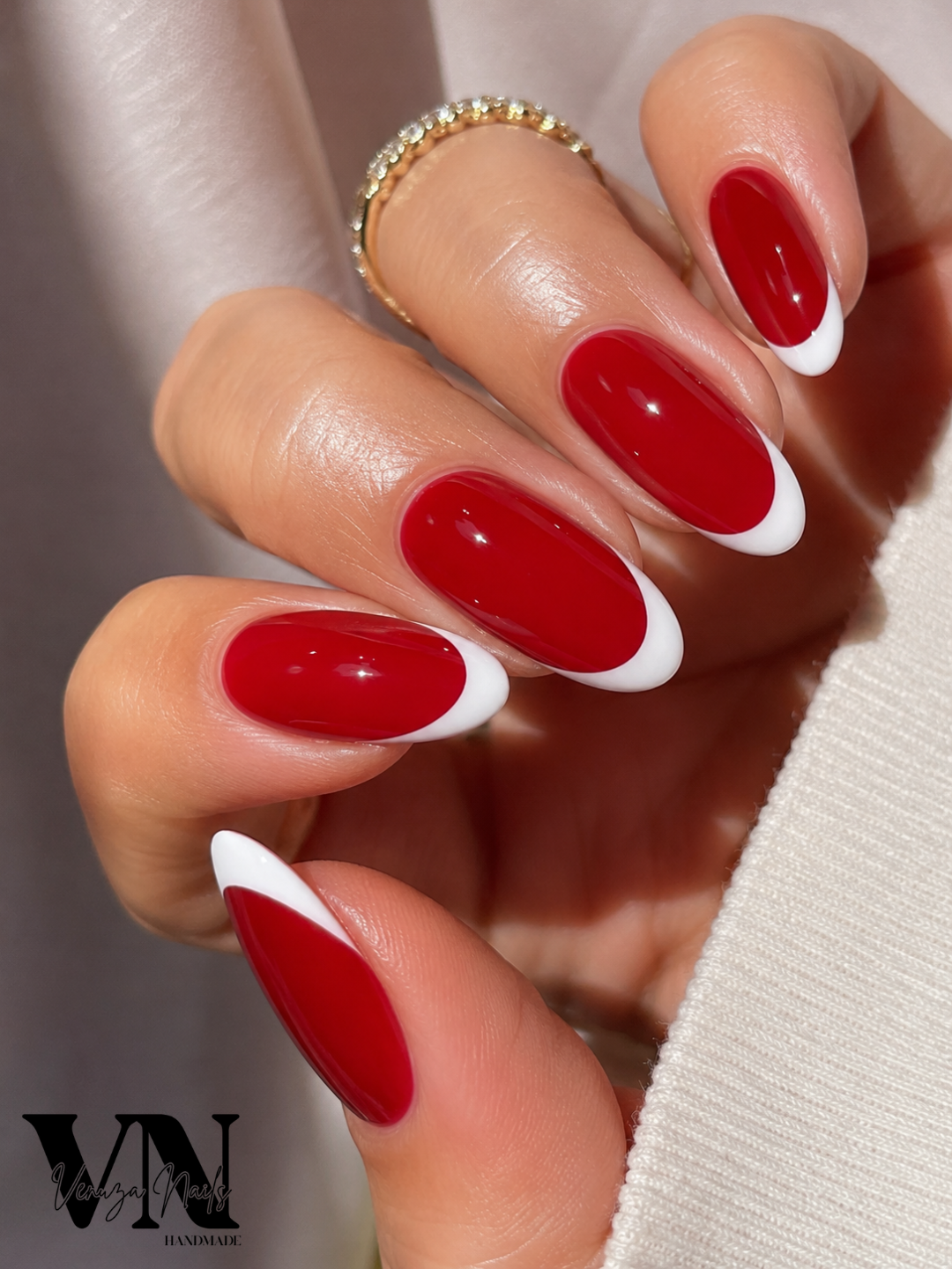 Main de femme présentant des press-on nails rouge rubis avec French blanche, manucure chic Venuza Nails